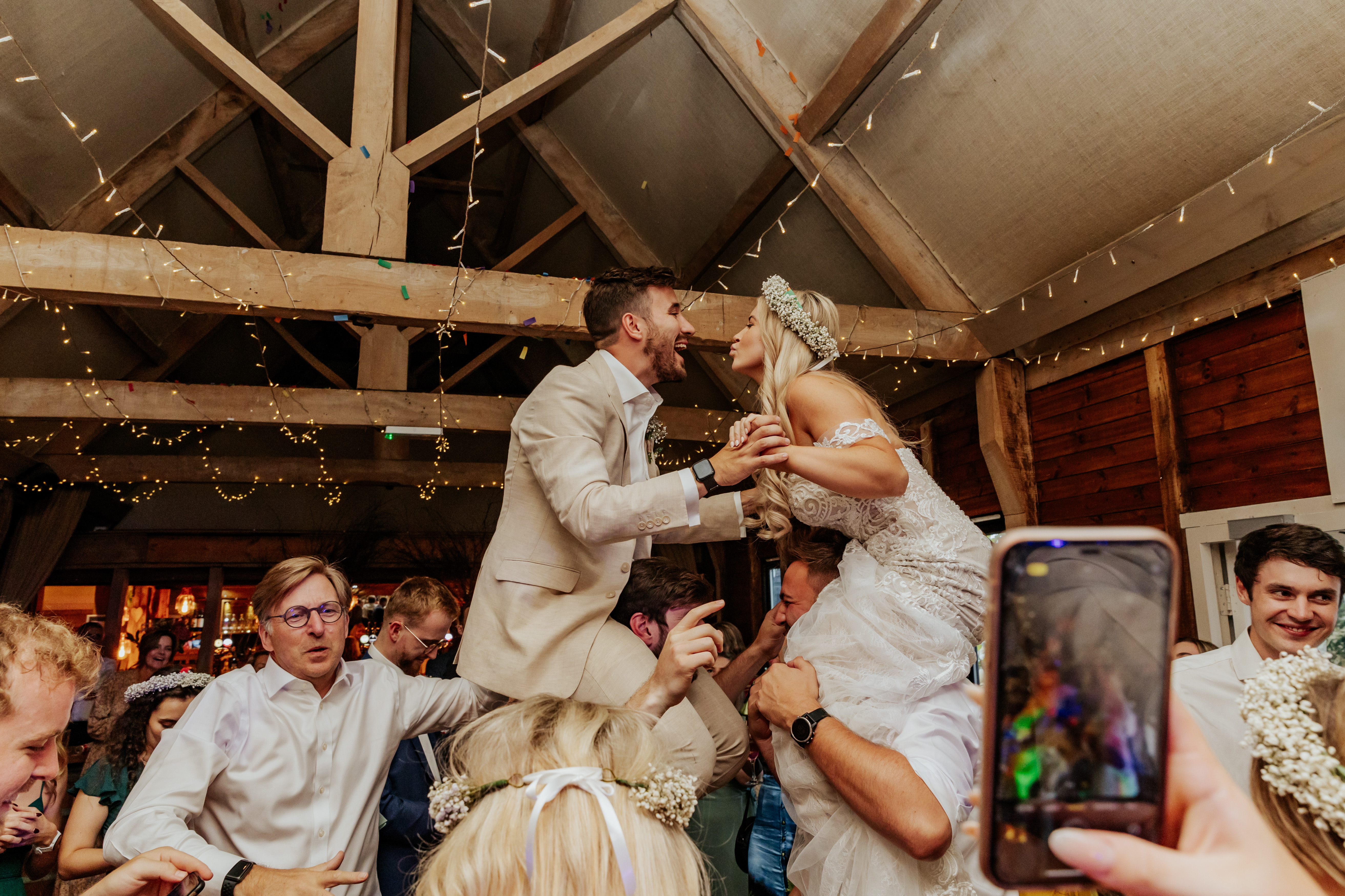 Bride and groom up on their guests shoulders during the party