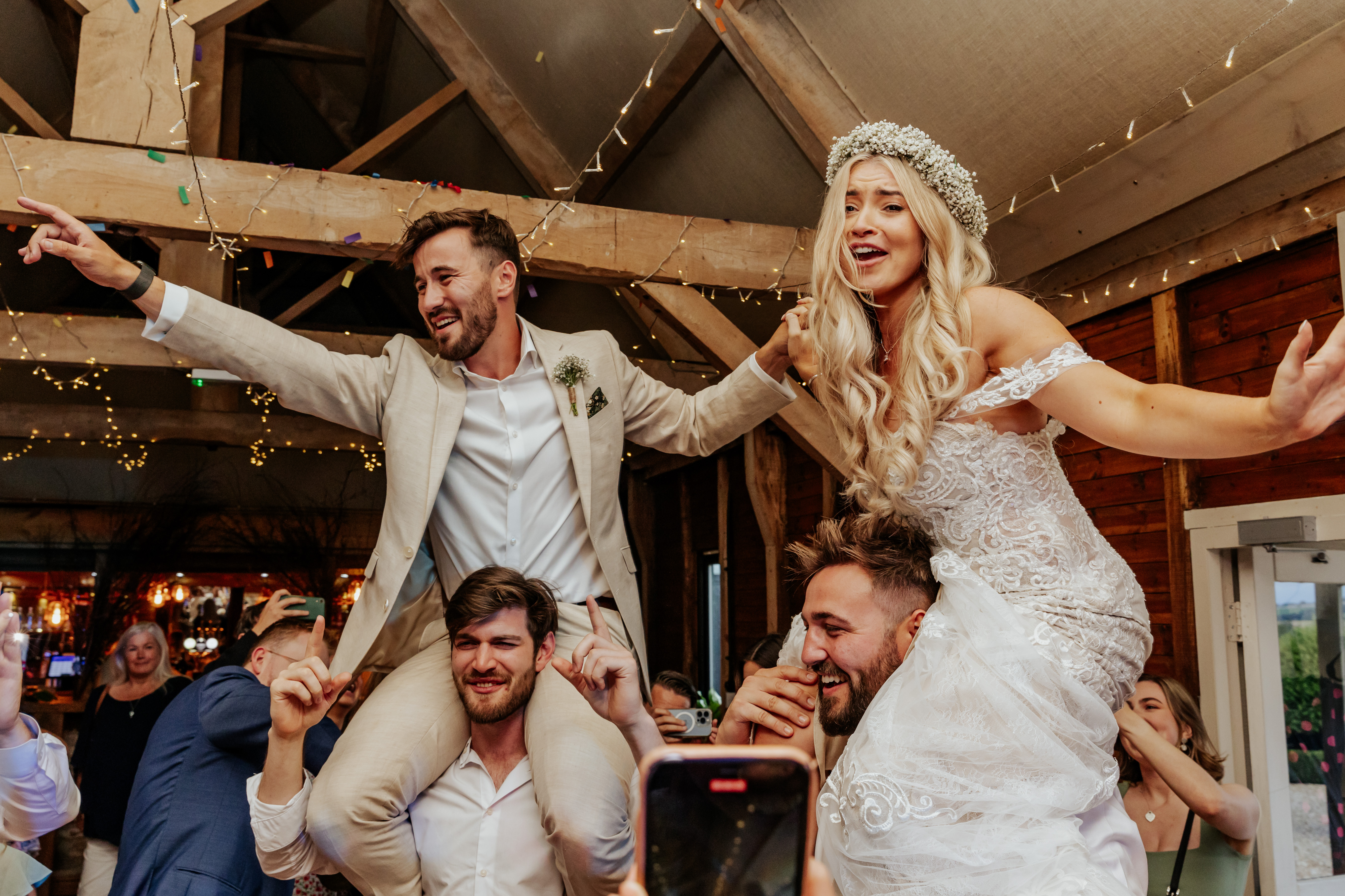 Bride and groom up on their guests shoulders during the party
