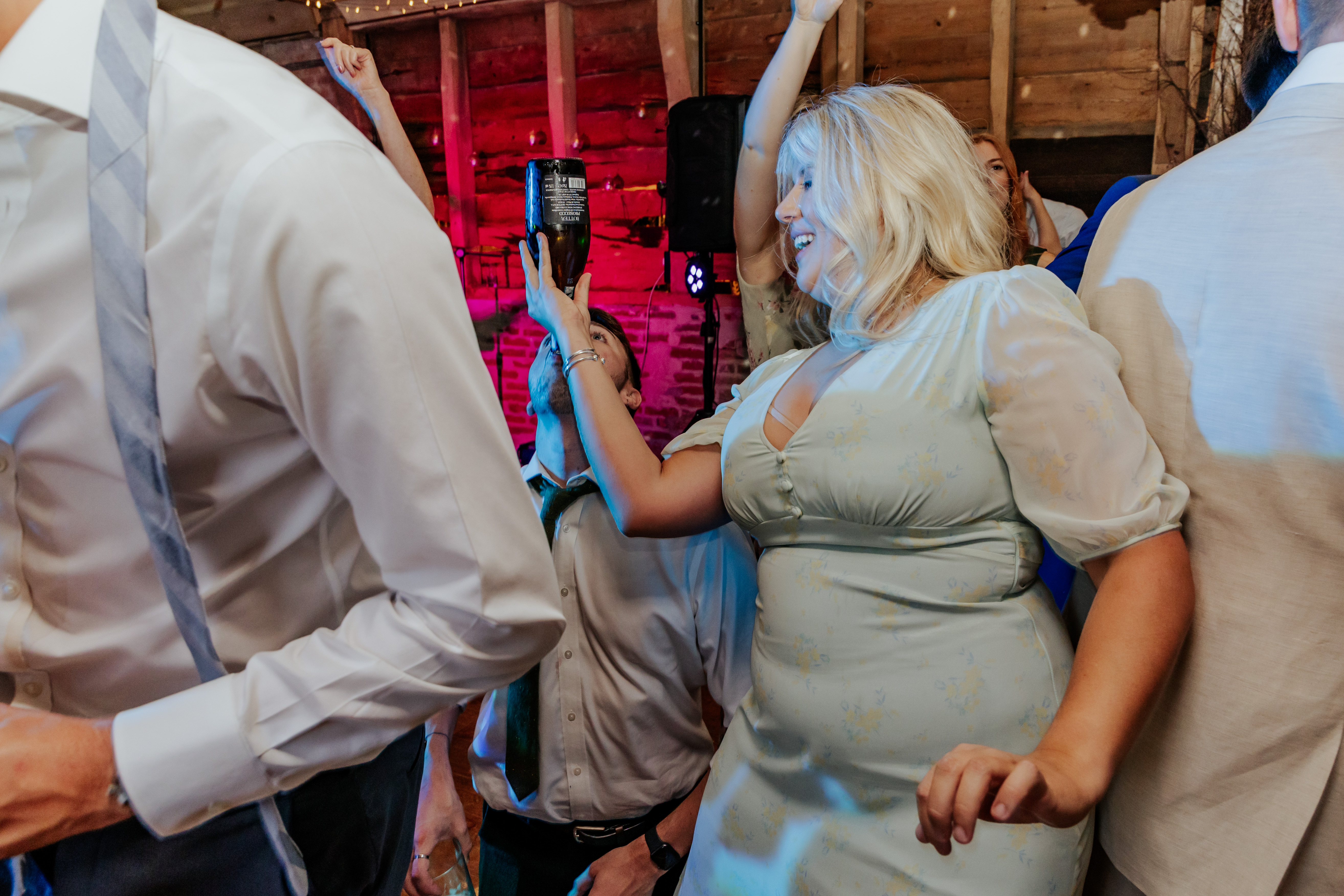 Bridesmaid pours prosecco into someone's mouth while dancing