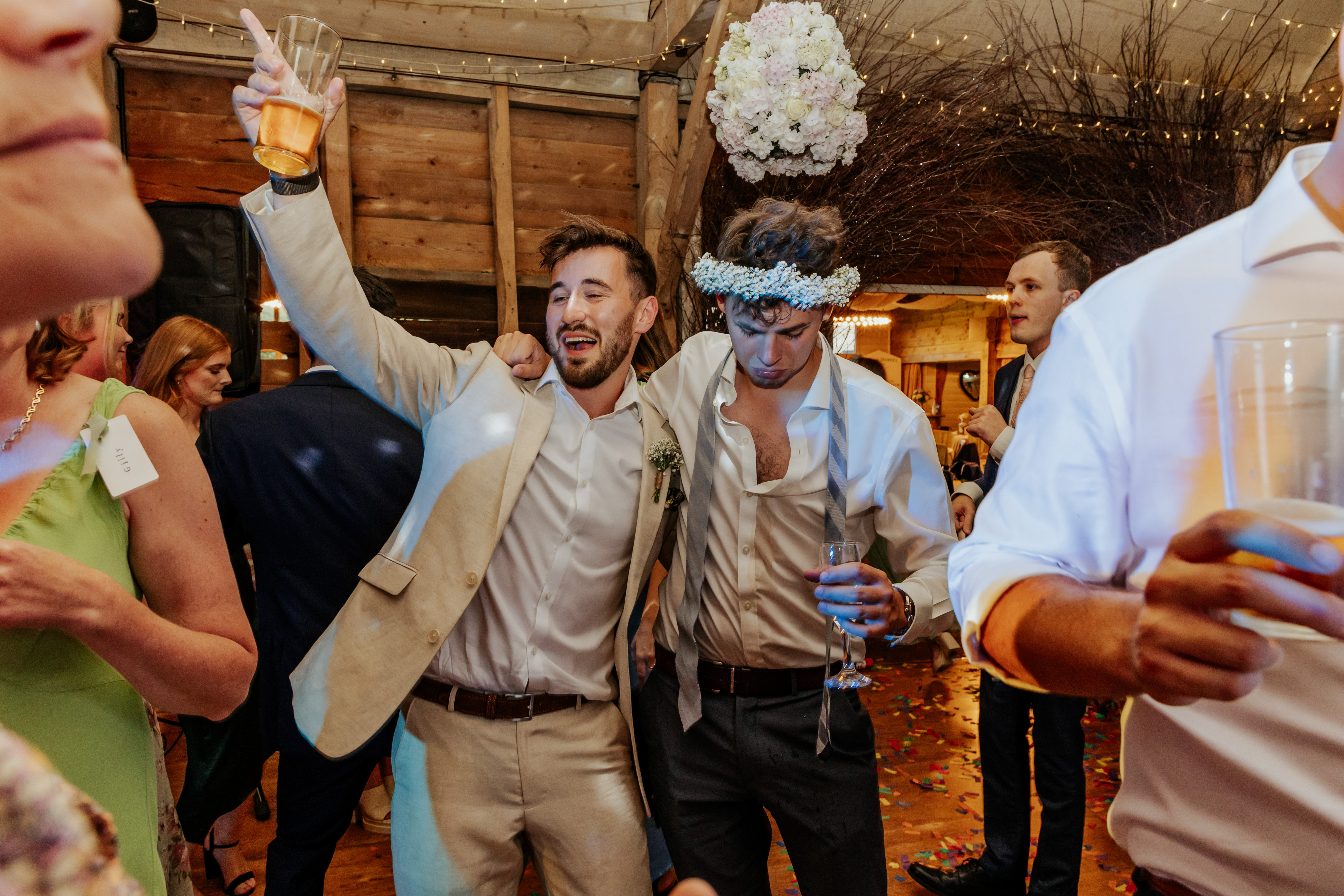 Groom dances with a guy wearing a bridesmaid's flower crown