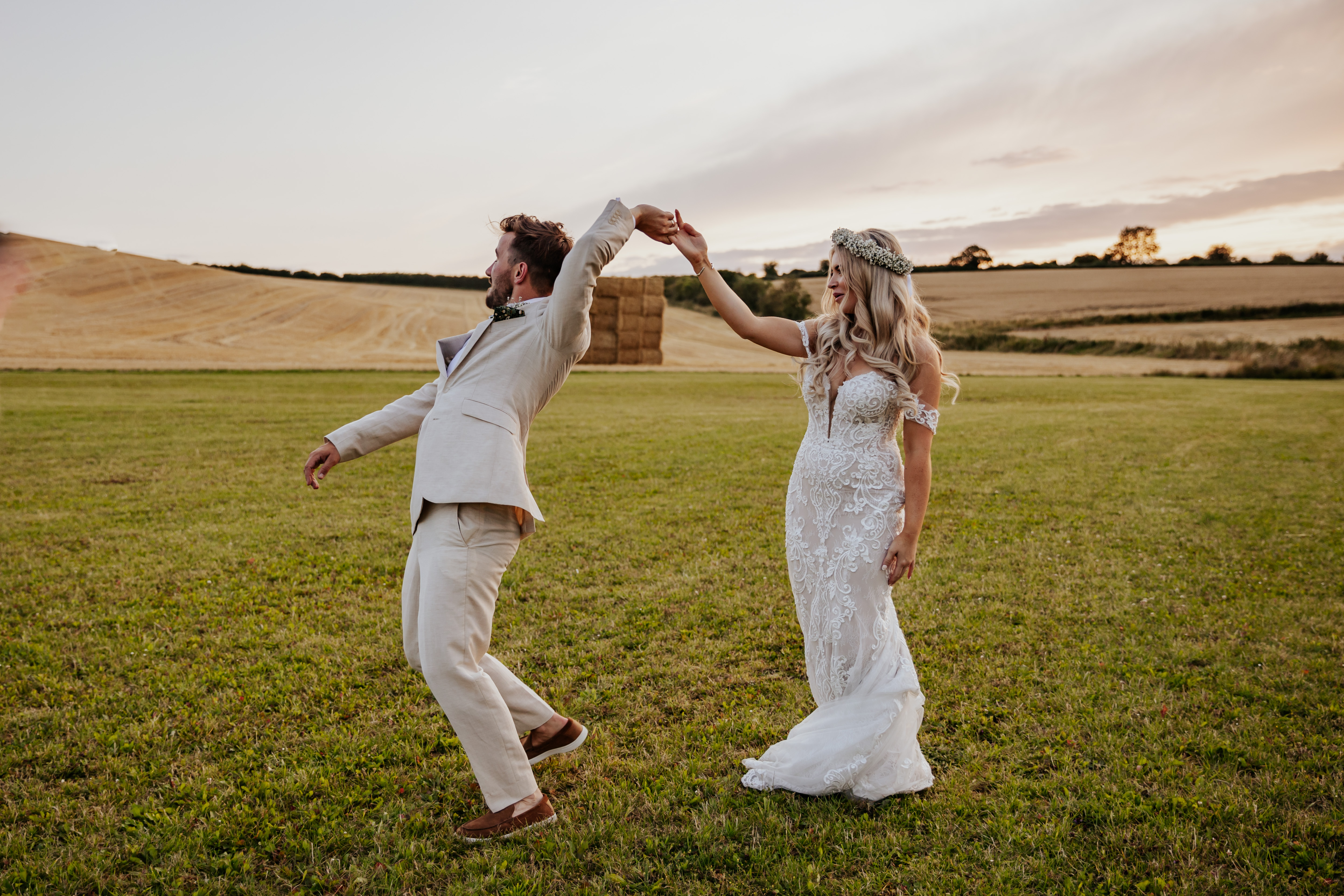 Bride and groom dance together in a field at golden hour